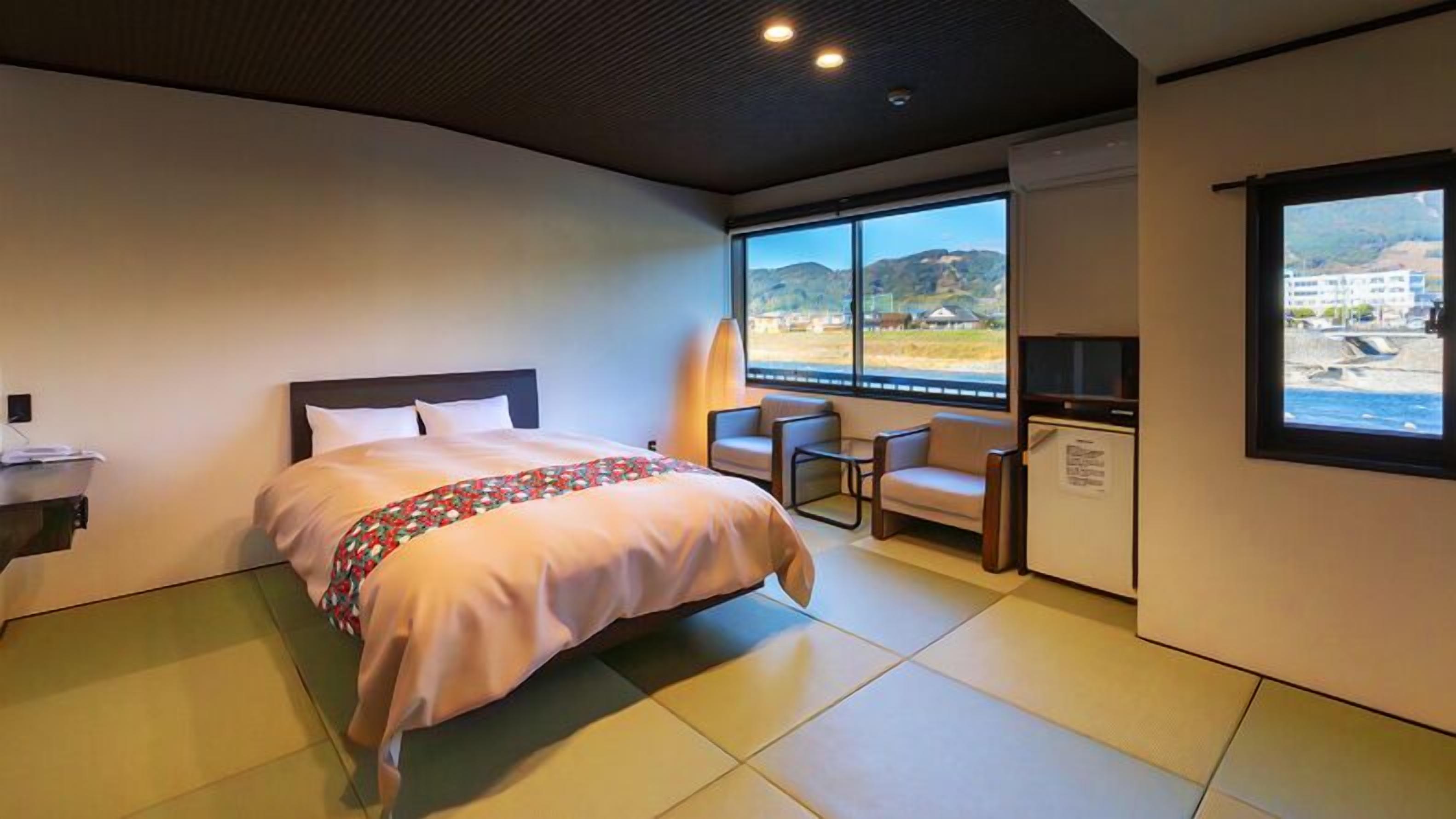 A hotel room with a bed, a desk, a chair, a TV, and a window with a view.