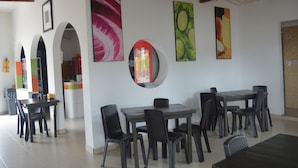 A dining area with tables and chairs, a refrigerator, and a Coca-Cola refrigerator. - Hotel Restaurante Versalles (Melgar)
