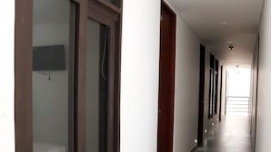 A long, narrow hallway with a tiled floor, wooden doors, and a flat-screen TV mounted on the wall. - Hotel Restaurante Versalles (Melgar)
