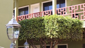 Un bâtiment à la façade verdoyante, avec une porte numérotée et un garde-corps aux motifs géométriques.