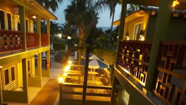 Un hôtel doté d’un escalier menant à un espace extérieur couvert, entouré d’immeubles avec des balcons et, au fond, d’un palmier.