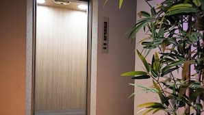 An elevator with a wooden interior and a control panel on the wall. - Personal Hotel You (Takeo)