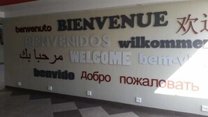 A wall with multilingual 'WELCOME' signs in various languages. - Hotel Eiffel (Ensenada)