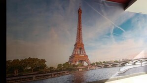 A mural of the Eiffel Tower with a river and bridge in the foreground. - Hotel Eiffel (Ensenada)