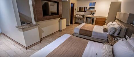 Una habitación de hotel con dos camas, una kitchenette, un televisor y un baño.