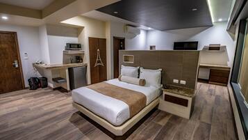 A modern hotel room with a bed, desk, and built-in storage.
