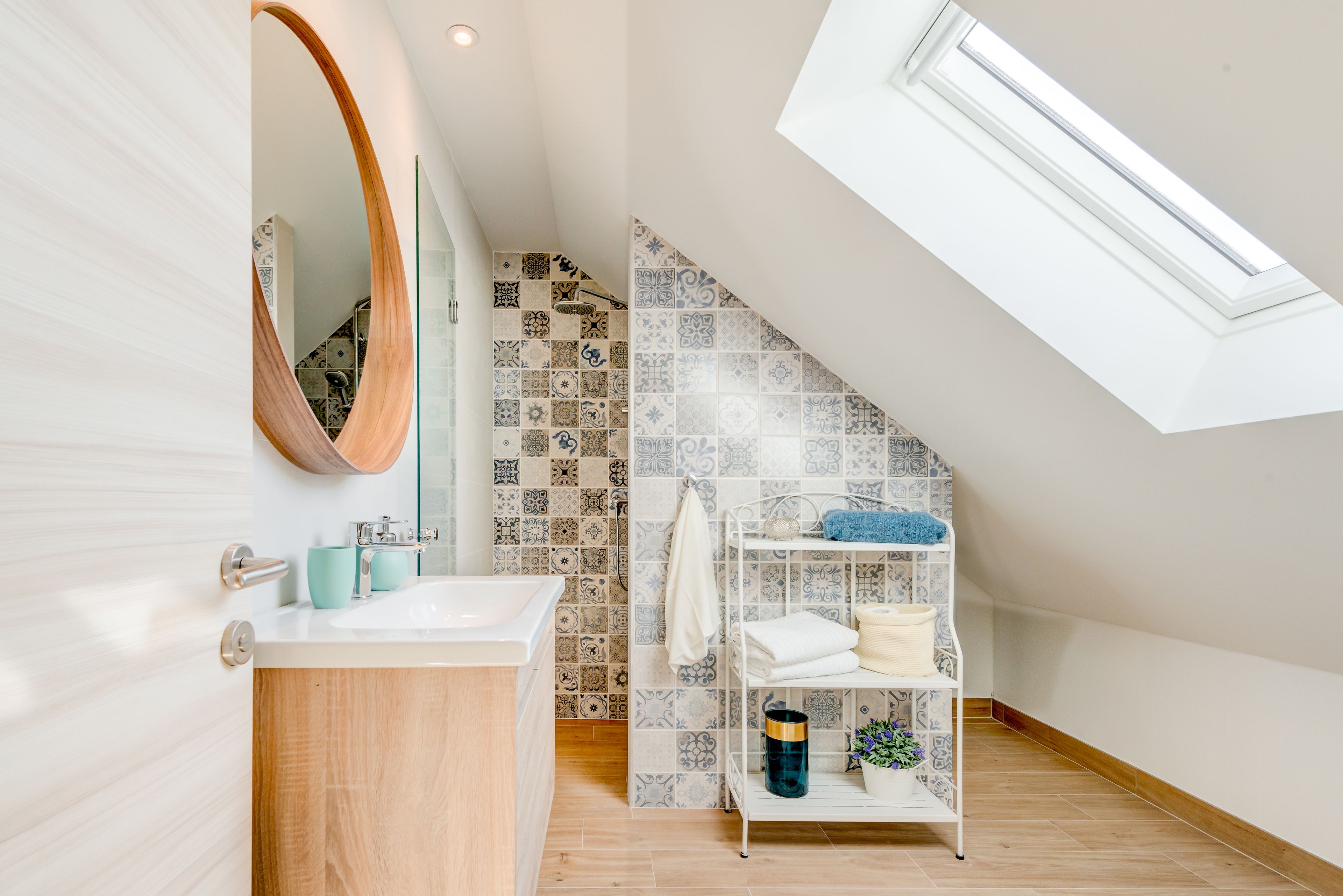 Ein modernes Badezimmer mit Oberlicht, einem Holz-Waschtisch, einem weißen Waschbecken und einer gefliesten Rückwand.