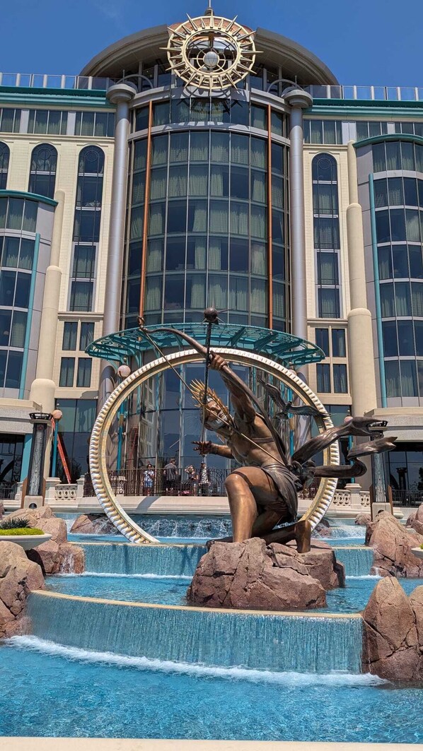 A large bronze statue of a sea creature with a circular frame in front of a modern building with large windows.