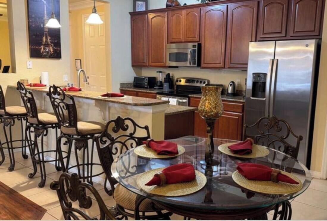 A kitchen with wooden cabinets, a stainless steel refrigerator, a microwave, and a coffee maker.
