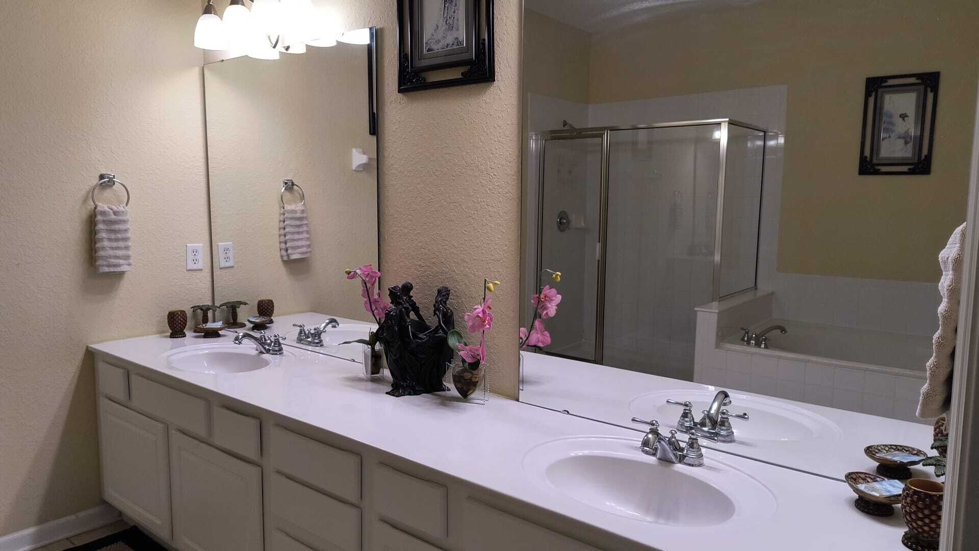 A bathroom with two sinks, a large mirror, and a shower.