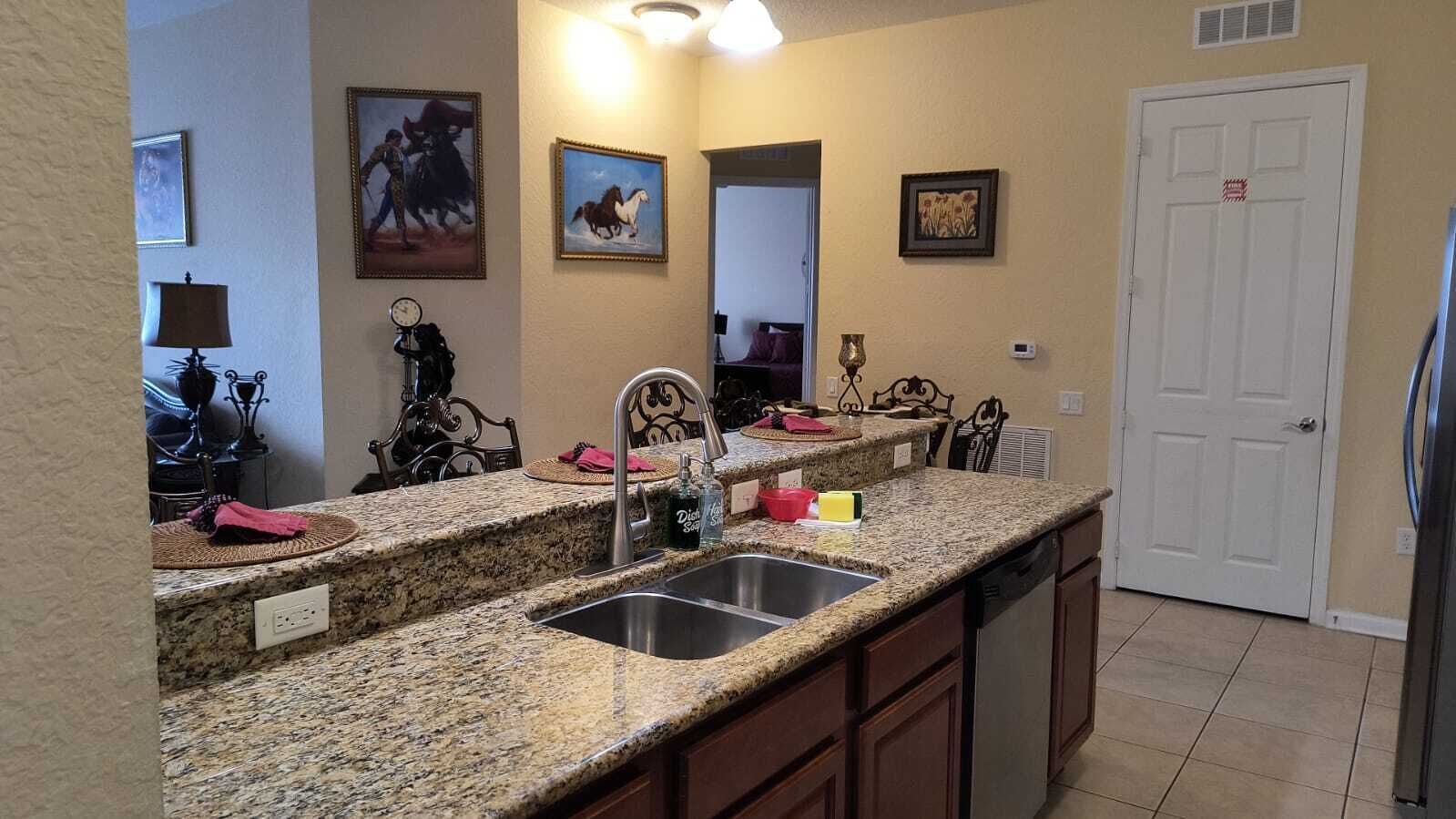 A kitchen with granite countertops, a double sink, and a refrigerator.