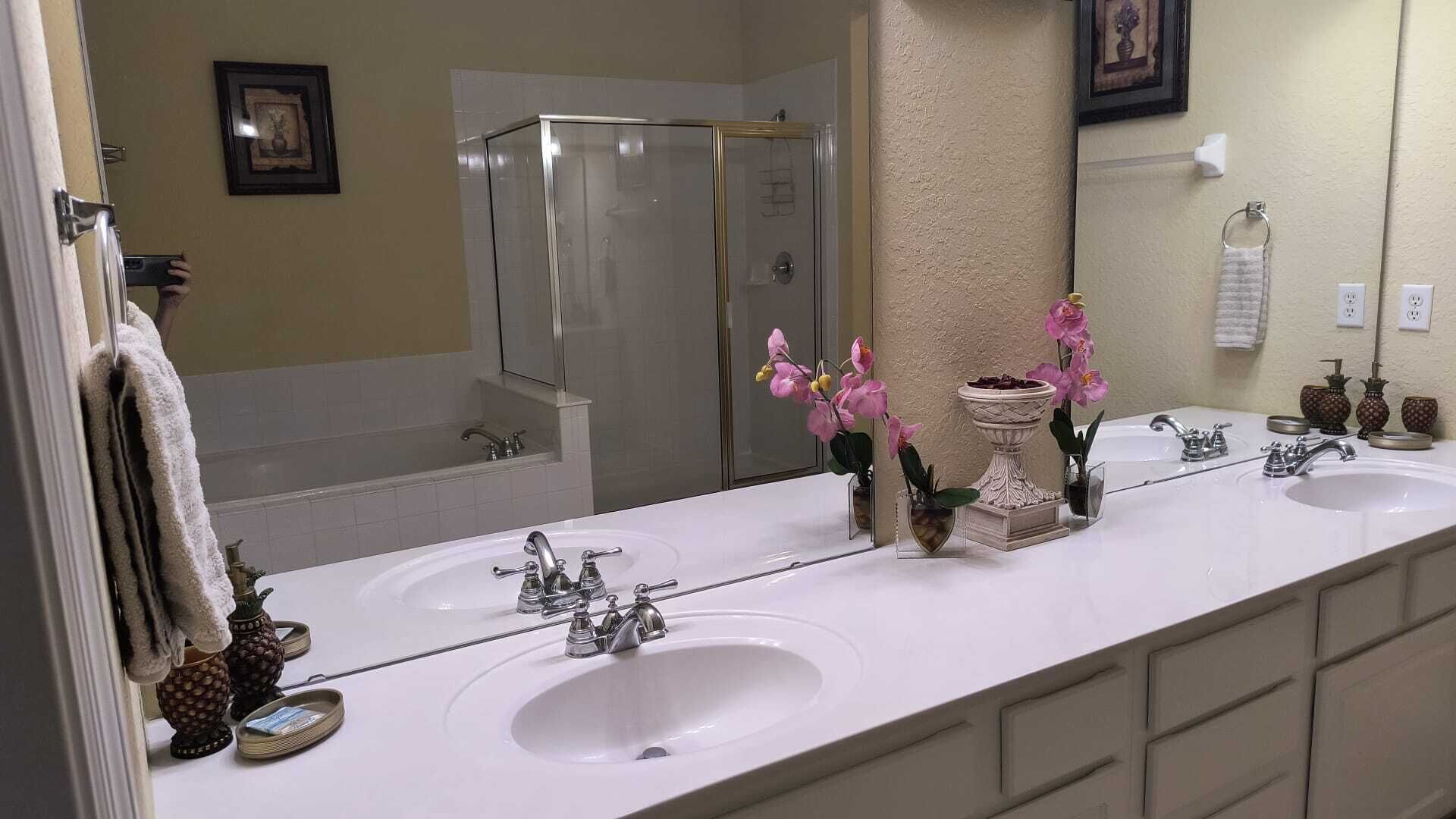 A bathroom with two sinks, a shower, and a large mirror.