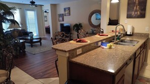 A kitchen with granite countertops, a sink, and a dining area with a table and chairs. - Executive 3 Br Villa @Universal / Vista Cay/Conv.Center (Orlando)