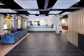 A modern reception area with a blue sofa, a reception desk, and a wooden partition. - Best Western Hotel Viernheim Mannheim (Viernheim)