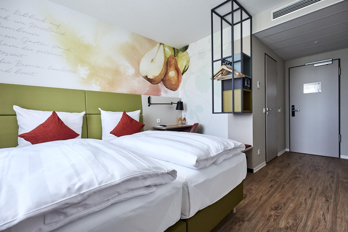 A hotel room with a bed, a desk, and a wardrobe.