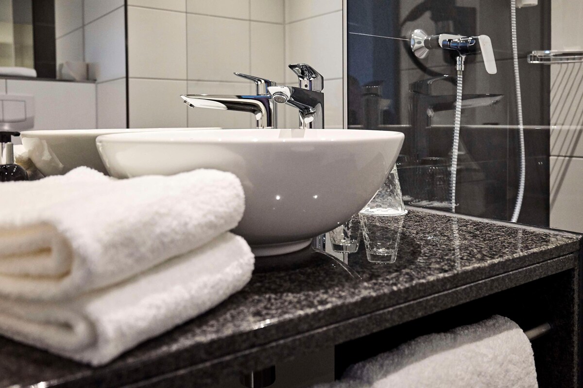 Un baño con lavamanos blanco, espejo y ducha.