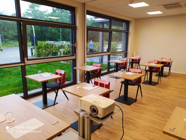 Un aula con amplios ventanales, escritorios y sillas de madera.