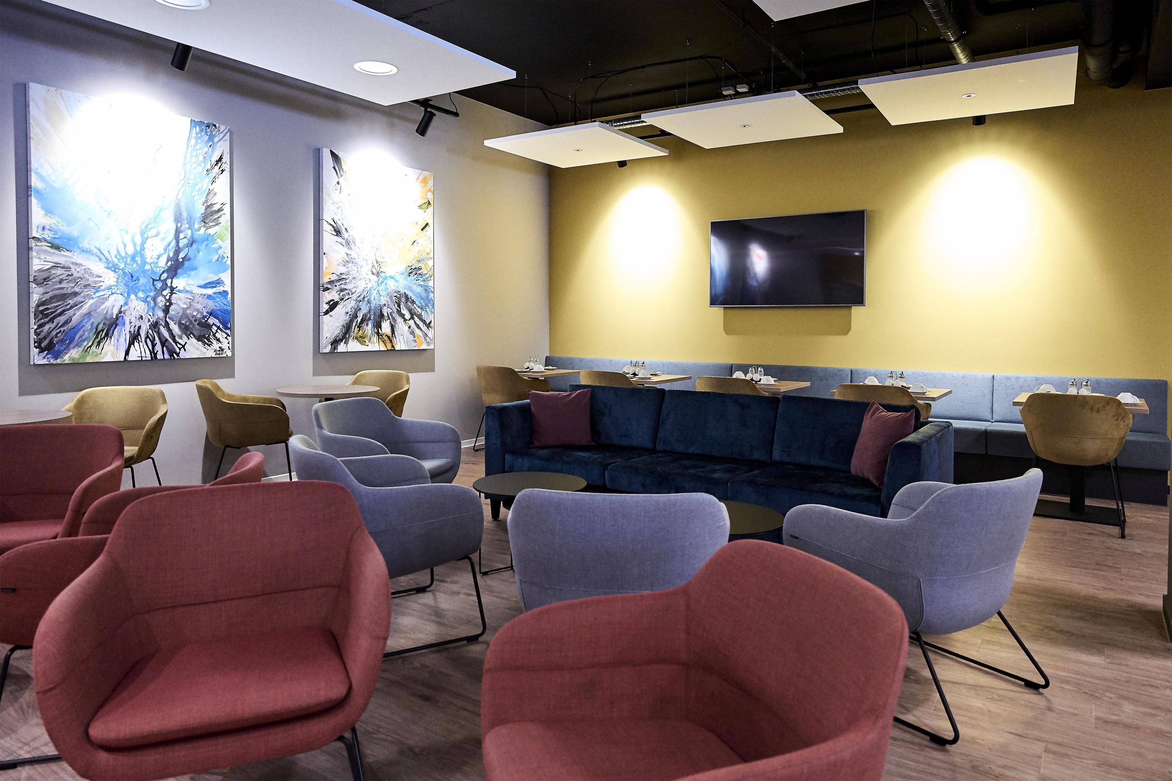 A modern waiting area with a sofa, chairs, and artwork on the walls.