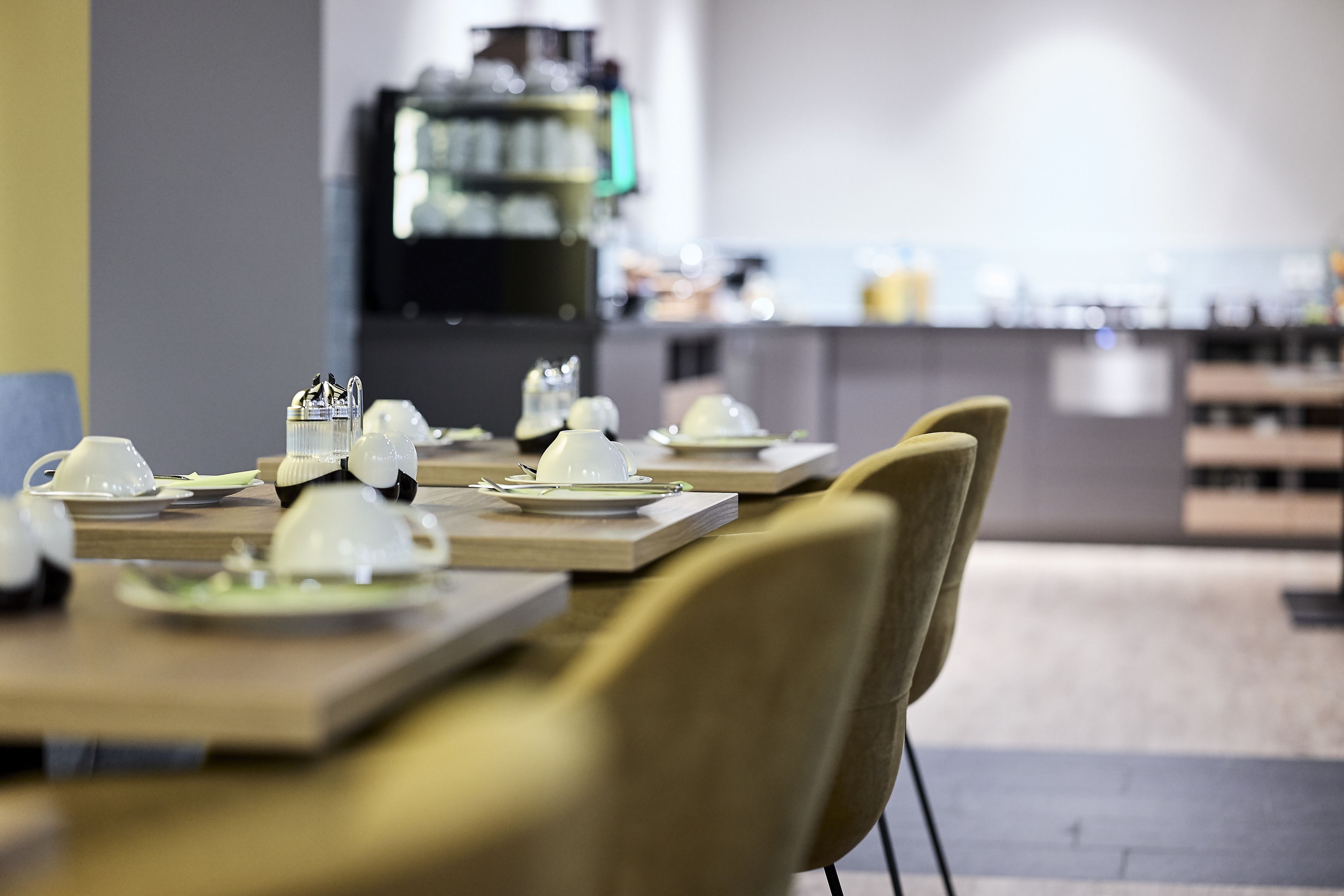 Un restaurante con mesas dispuestas para comer, sillas y una barra al fondo.