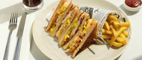 Ein Teller mit einem Sandwich, Pommes, einer Gabel, einem Messer und einem Glas Limonade.