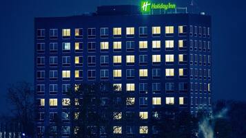 Ein mehrstöckiges Gebäude mit beleuchteten Fenstern und einem gut sichtbaren 'Holiday Inn'-Schild auf dem Dach.