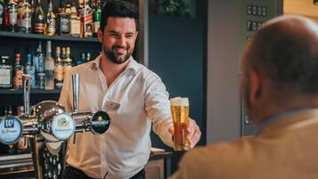 A bartender serving a beer to a customer in a bar with shelves of liquor bottles in the background.