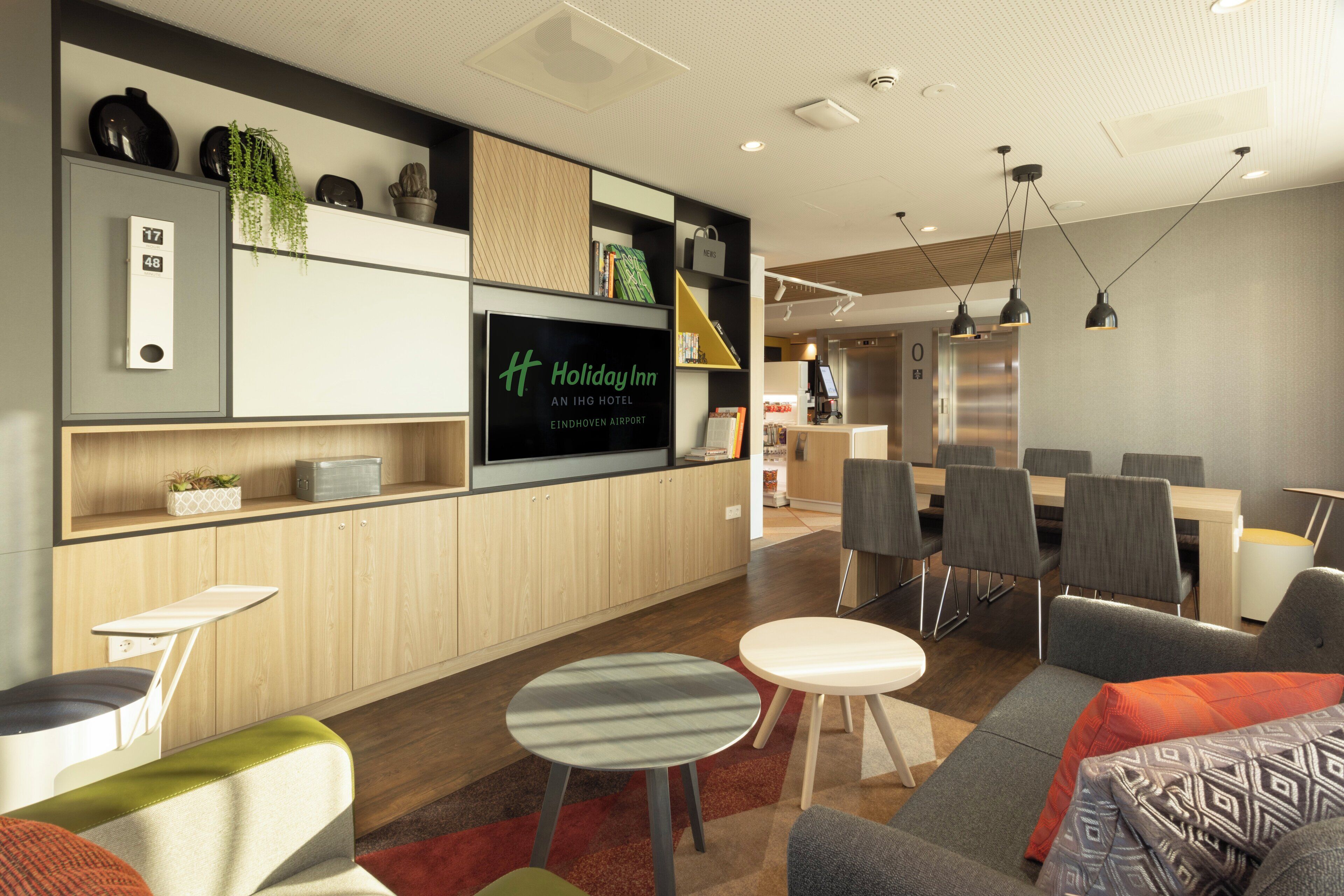 Un moderno vestíbulo de hotel con televisor de pantalla plana, zona de estar y kitchenette.