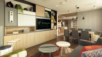 Un moderno vestíbulo de hotel con televisor de pantalla plana, zona de estar y kitchenette.
