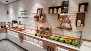 A buffet area with various food options, including bowls of fruits and vegetables, and shelves with condiments and beverages. - Holiday Inn Eindhoven Airport by IHG (Eindhoven)