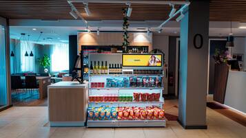 En modern butik med ett centralt placerat utbud av snacks och drycker, en digital informationsskylt och en ren och välordnad inredning.
