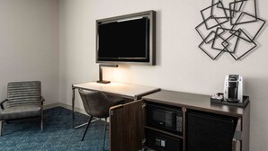 A hotel room with a desk, chair, flat-screen TV, coffee maker, microwave, and a decorative wall piece. - Holiday Inn Express Boston South - Quincy by IHG (Quincy)