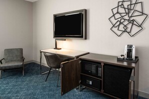 A hotel room with a desk, chair, flat-screen TV, coffee maker, microwave, and a decorative wall piece. - Holiday Inn Express Boston South - Quincy by IHG (Quincy)