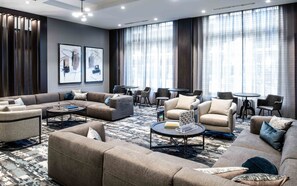 A modern hotel lounge with a sectional sofa, armchairs, a coffee table, and a patterned rug.