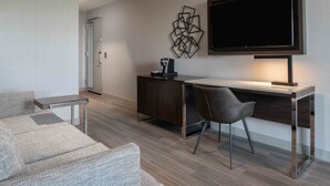A modern hotel room with a sofa, a desk, and a flat-screen TV. - Holiday Inn Express Boston South - Quincy by IHG (Quincy)