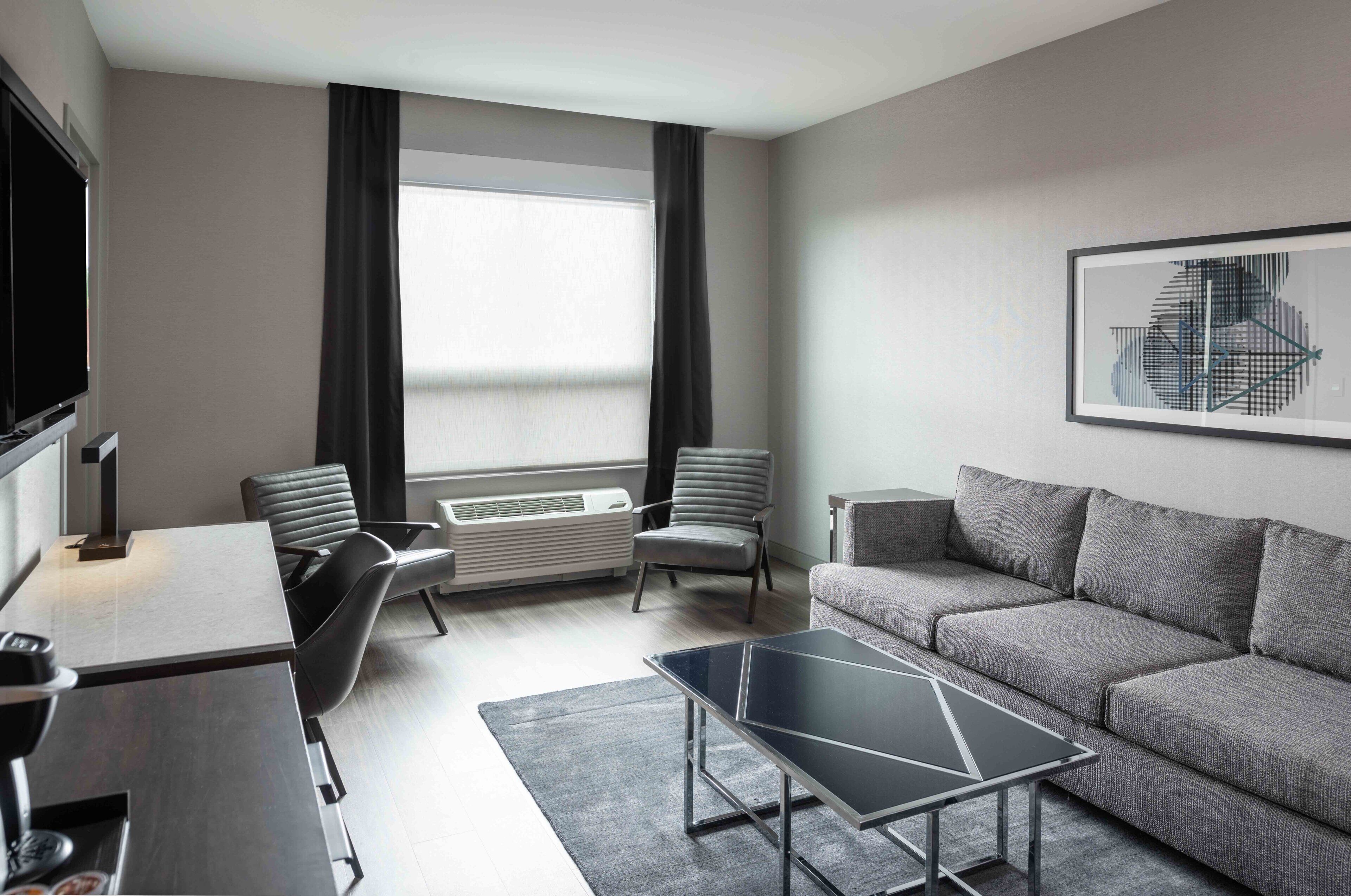 Een moderne woonkamer met een bank, twee fauteuils, een salontafel, een televisie en een radiator.