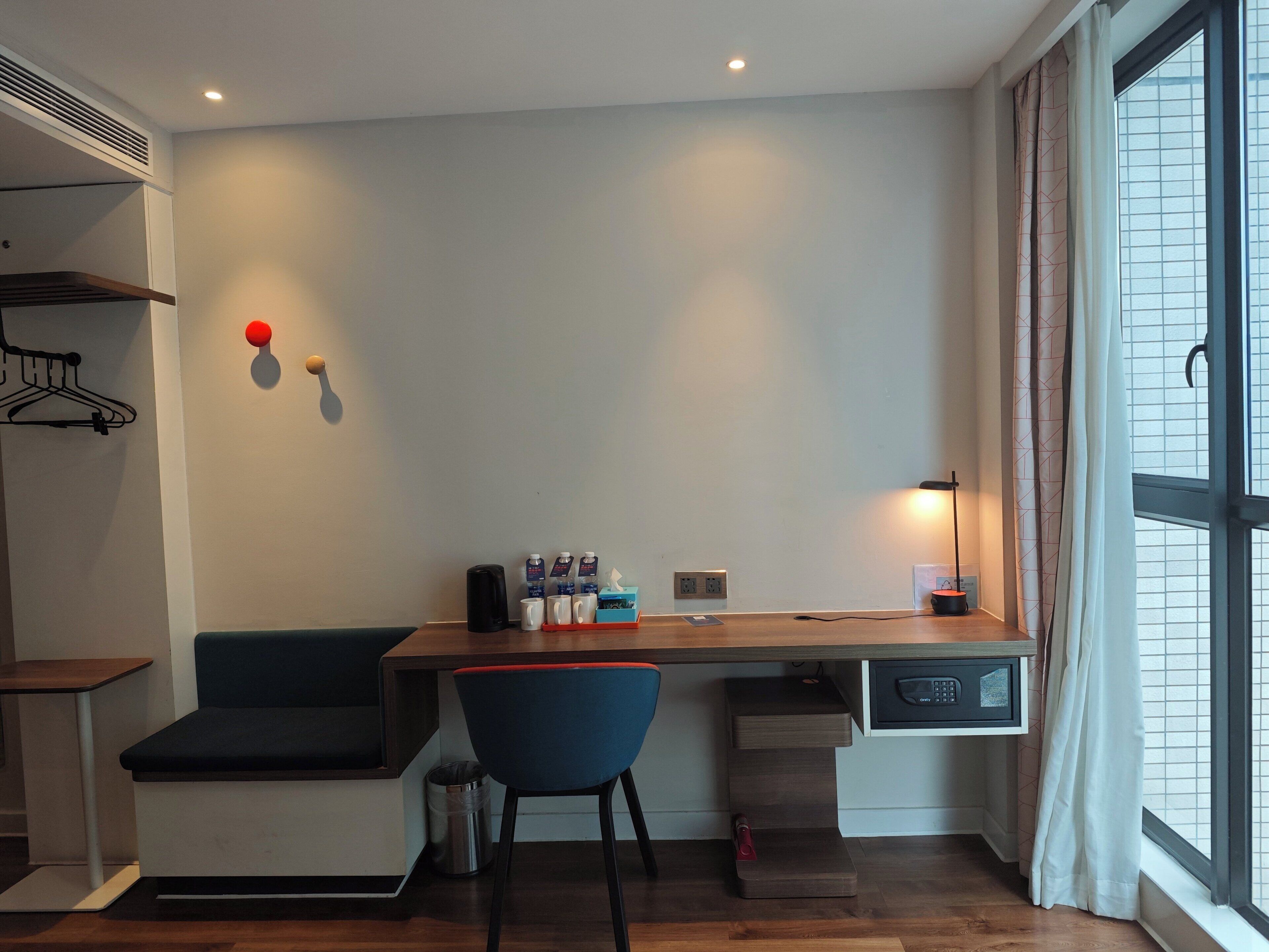 Un espacio habitable compacto con kitchenette, zona de estar y ventana con cortinas.