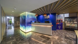A modern reception area with a marble floor, a reception desk, and a blue wall with geometric patterns.