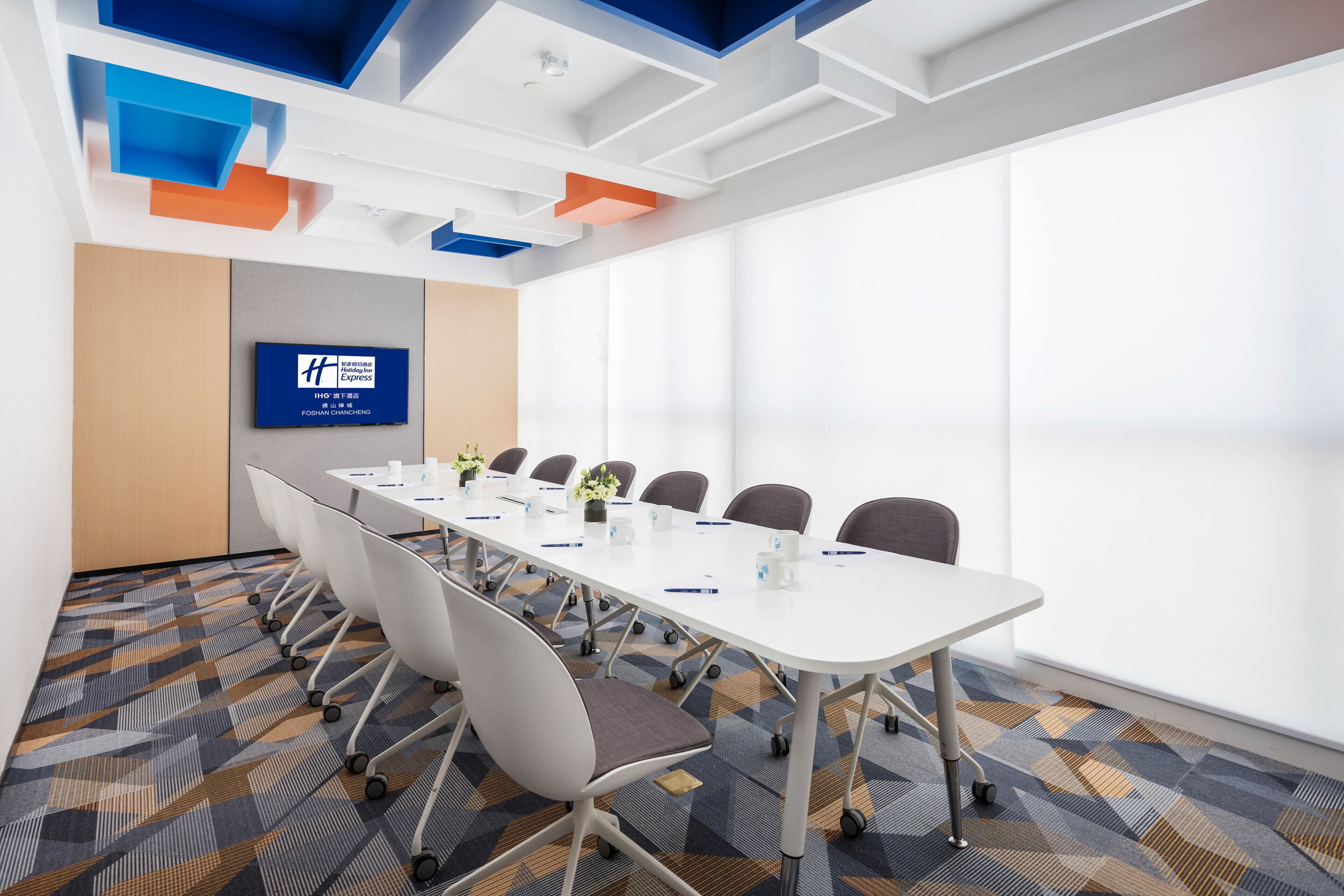 A conference room with a long table, chairs, and a blue sign on the wall.