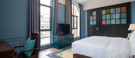 Un dormitorio con una cama grande, televisión, cómoda y una silla.