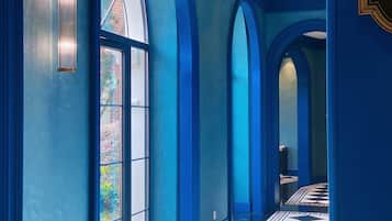 Un pasillo con paredes azules y ventanas amplias.