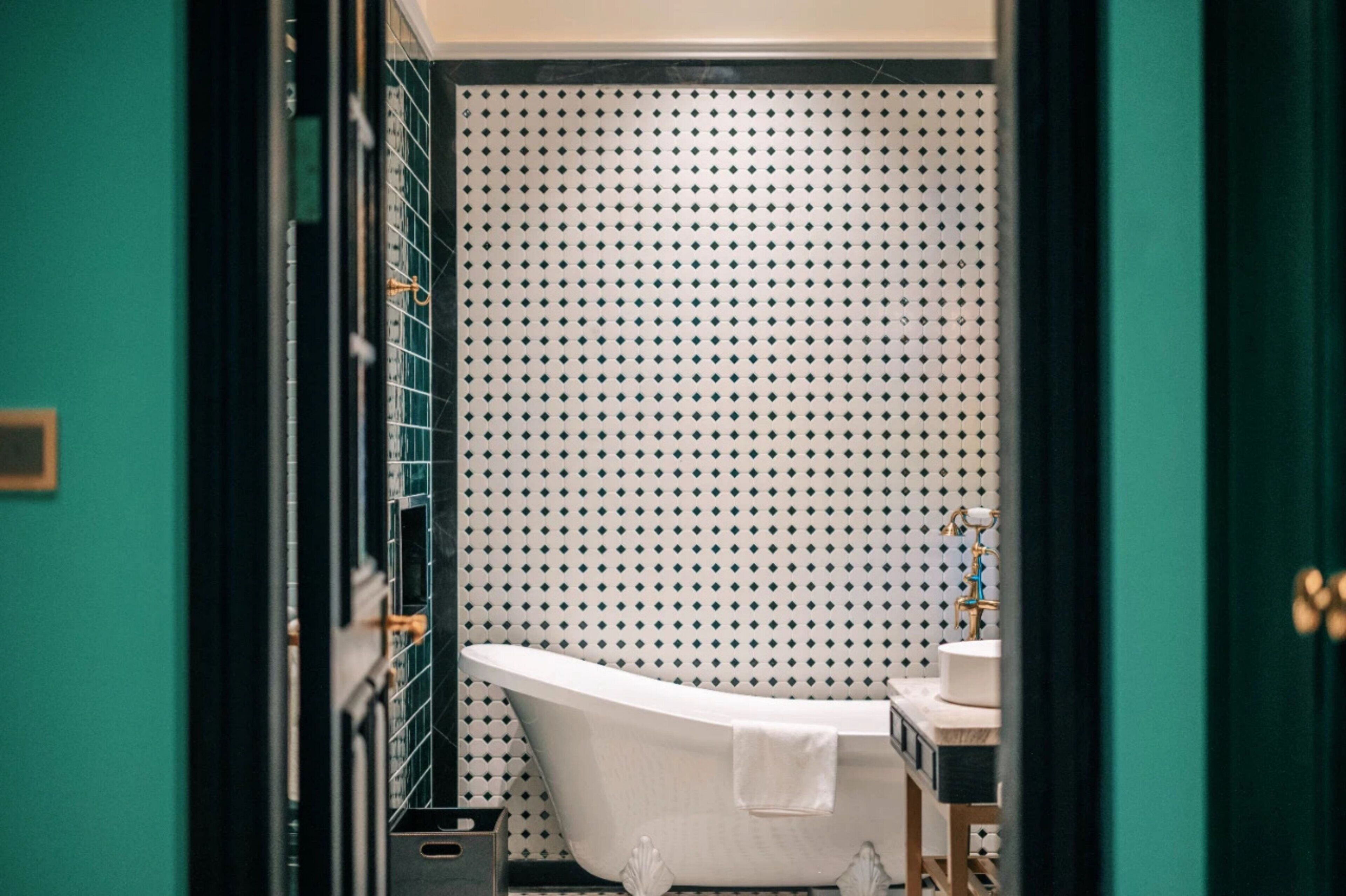 A bathroom with a freestanding bathtub, a sink, and a tiled wall with a diamond pattern.