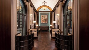 A hallway with a central seating area, flanked by two tables with lamps, leading to a room with a large painting. - Hotel Indigo Heilong Lake by IHG (Meishan)