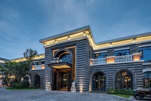 A hotel entrance with a stone facade, a sign reading 'Hotel Indigo', and a lion statue in front.