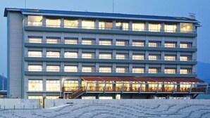 A multi-story hotel with a flat roof, large windows, and a covered outdoor area with steps leading to the entrance. - Izumatsuzaki Sou (Matsuzaki)