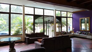 Un'ampia zona giorno con grandi finestre, una panca integrata e un tavolo con piano in vetro.