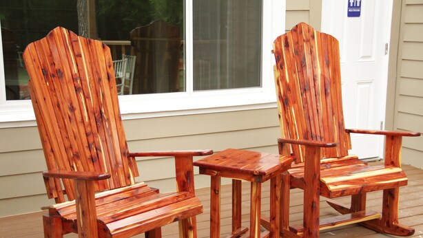 Deux fauteuils à bascule en bois, posés sur une terrasse également en bois.
