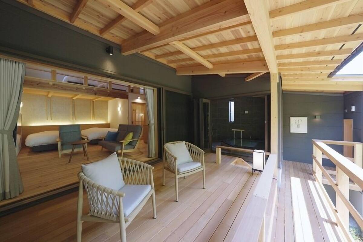 A wooden deck with wicker chairs, a sofa, and a small table.