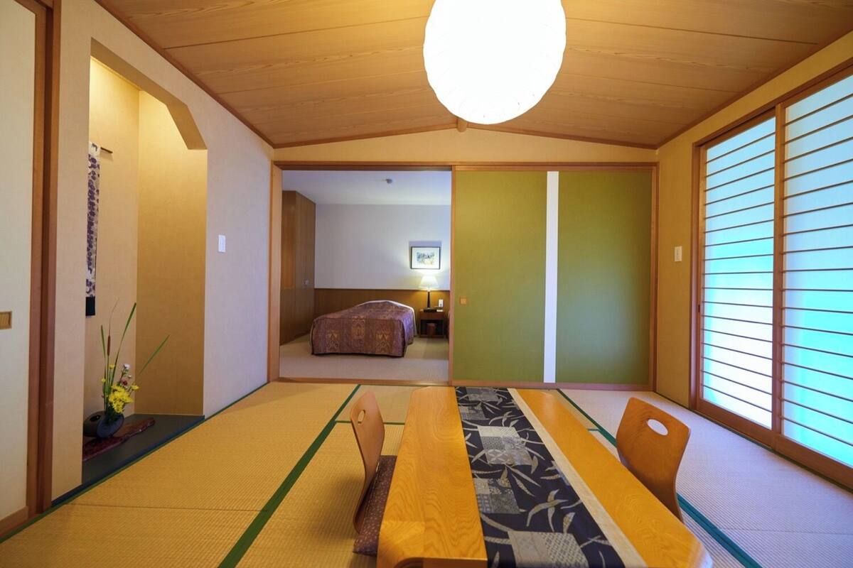 A traditional Japanese room with tatami flooring, a low table, and sliding doors.