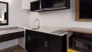 Une cuisine moderne dotée d’un plan de travail en granit, de meubles de rangement noirs, d’un évier en acier inoxydable et d’un four à micro-ondes encastré.