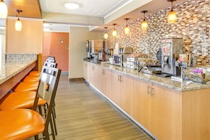 Une cuisine moderne dotée d’un long comptoir, de tabourets de bar et de divers appareils électroménagers.